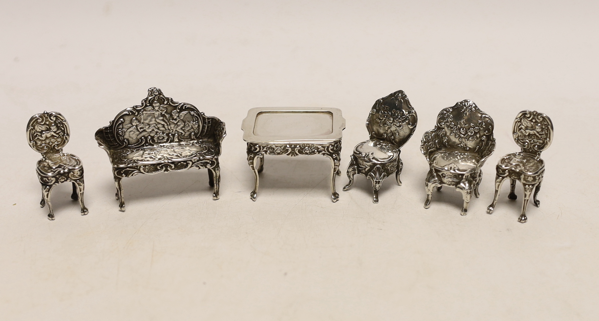 An Edwardian miniature table, 45mm and single chair, by Levi & Salaman, Birmingham, 1902, a later silver single chair, two other white metal miniature chairs and a similar settee.